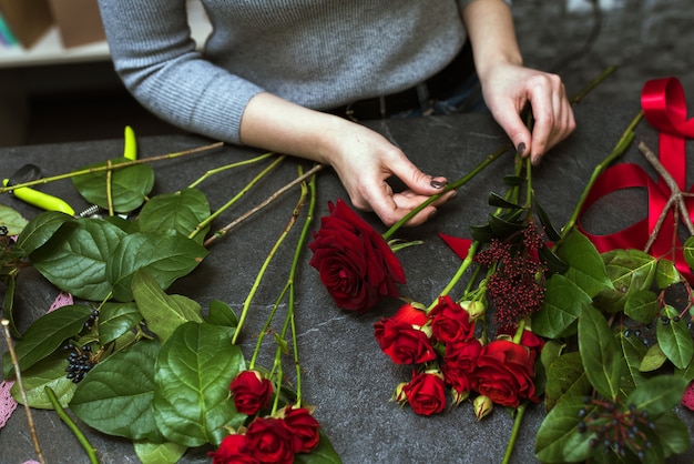 Piękna Kobieta Zbiera Ciemny Bukiet Czerwonych Bordowych Róż. Leżał Płasko, Widok Z Góry. Dostawa Kwiatów, Tworzenie Zamówienia, Mała Firma