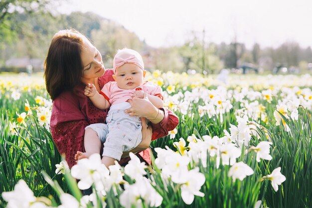Piękna kochająca matka i dziewczynka w polu kwiatów żonkili na wiosnę Młoda kobieta z jej uroczą córeczką bawi się na świeżym powietrzu Rodzina na przyrodzie w Arboretum Słowenia