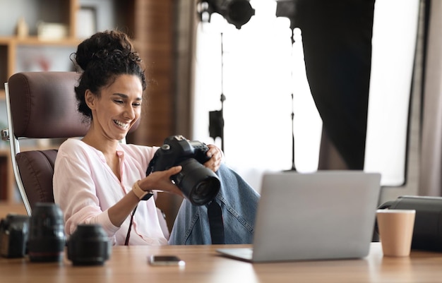 Piękna kreatywna kobieta fotograf pracująca przy użyciu laptopa i aparatu