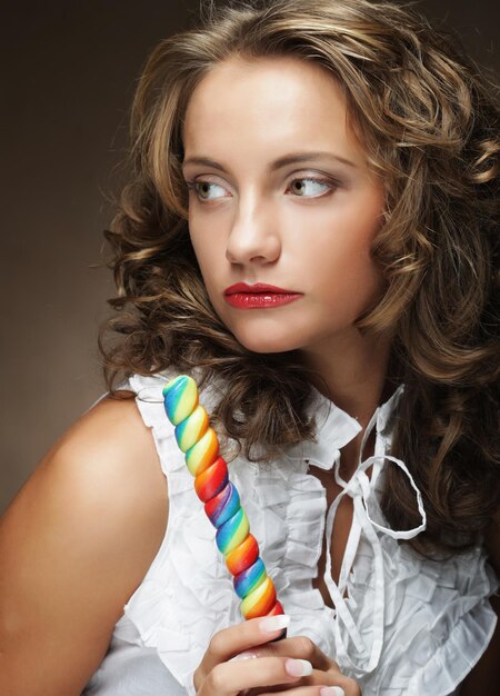 Piękna kręcona dziewczyna portret trzymająca kolorowy lizak