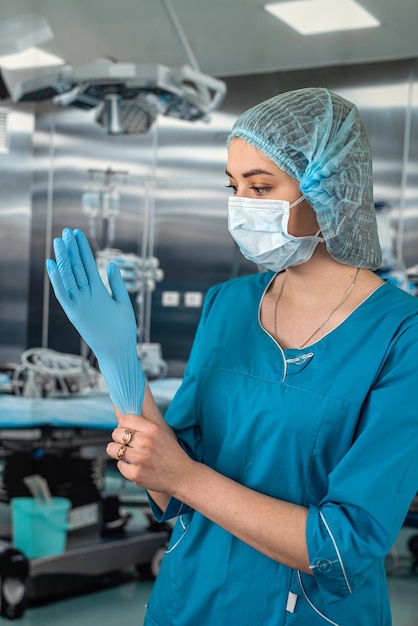 Piękna lekarka chirurg w rękawiczkach medycznych stojąca w sali operacyjnej