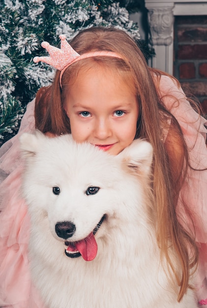 Piękna Mała Blondynka Uśmiecha Się Z Białym Zabawnym Psem Samoyed