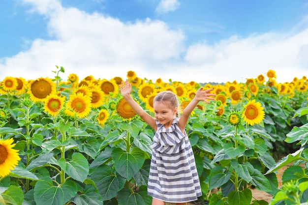 Piękna mała dziewczynka ciesząca się przyrodą Szczęśliwa uśmiechnięta kobieta dziecko stojąca w polu słoneczników
