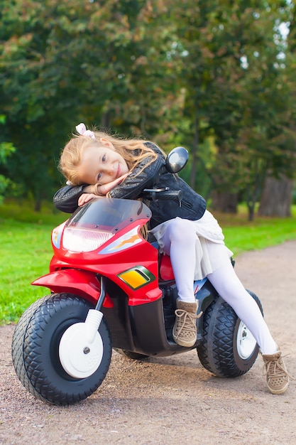 Piękna mała dziewczynka ma zabawę na jej zabawkarskim motocyklu