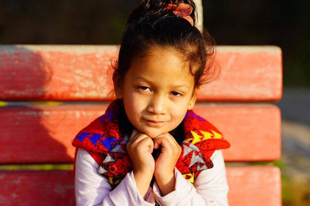 Piękna mała dziewczynka patrząca trzymając się za ręce, indyjska dziewczyna siedząca na zewnątrz