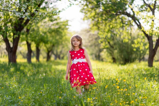 Piękna mała dziewczynka spaceruje po ogrodzie wśród drzew wiosną