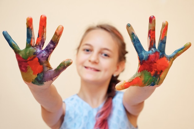 Piękna mała dziewczynka w białej koszulce pokazującej ręce z kolorowymi palmami patrząc na kamerę, selektywne focus