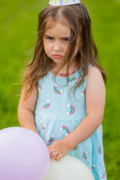 Piękna mała dziewczynka w niebieskiej sukience i kapeluszu z balonami w parku wszystkiego najlepszego z okazji urodzin