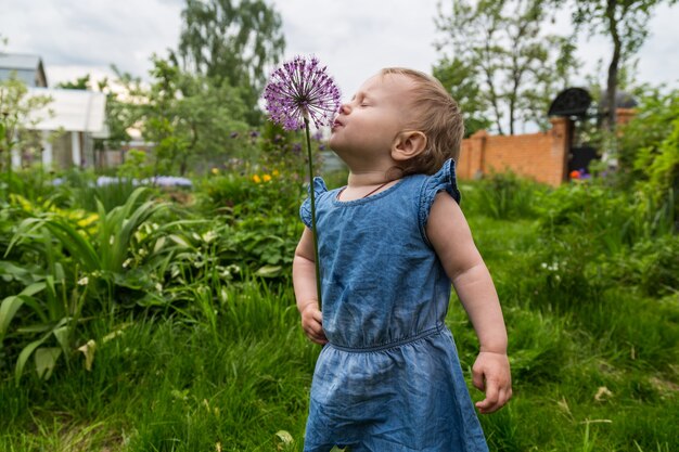 Piękna mała dziewczynka wącha kwiat w ogrodzie