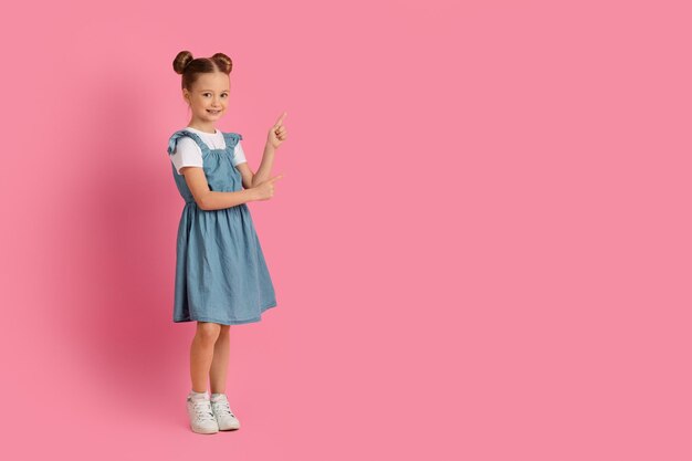 Piękna mała dziewczynka wskazuje ręką na bok przy kopii przestrzenią