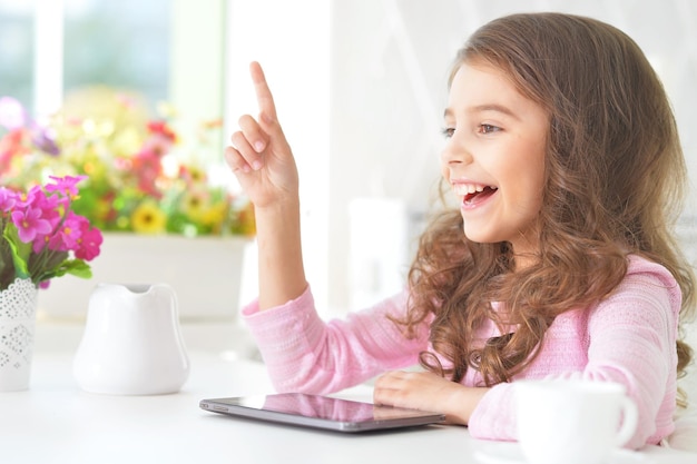 Piękna mała dziewczynka z komputerem typu tablet
