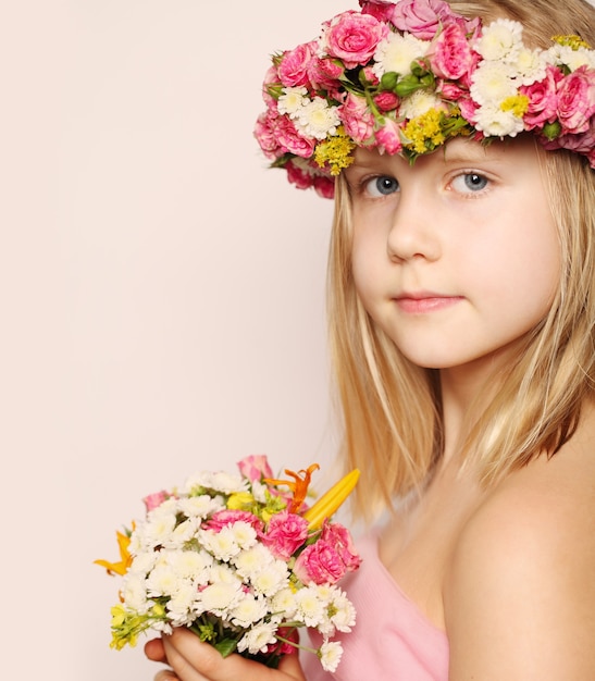 Piękna mała dziewczynka z kwiatami, pozowanie i patrząc