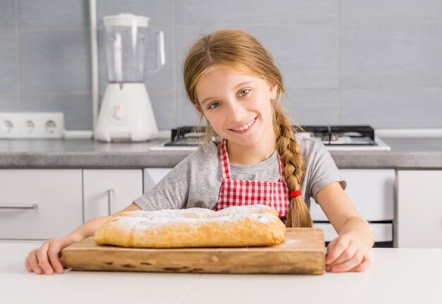 Piękna mała dziewczynka z piec jabłczanym strudlem na stole