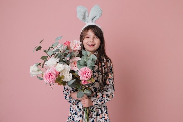 Piękna mała dziewczynka z uszami królika trzymająca kwiaty