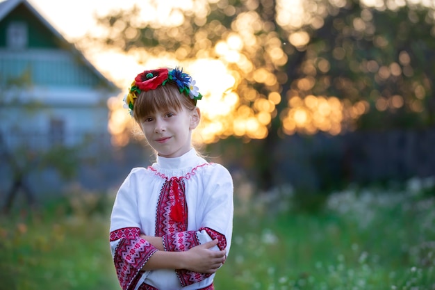 Piękna mała słowiańska dziewczyna w narodowych strojach na tle bokeh