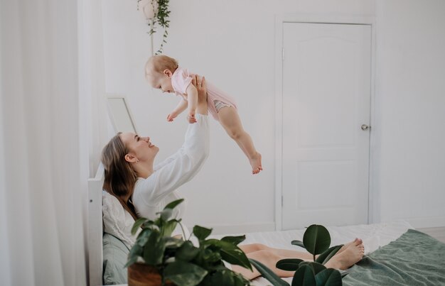 Piękna mama i córka bawią się na łóżku w sypialni