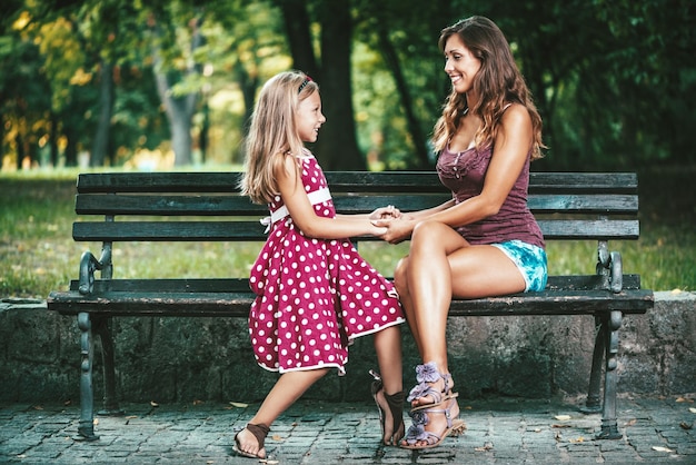 Piękna mama i córka bawią się w parku w wiosenny dzień, trzymając się za ręce.