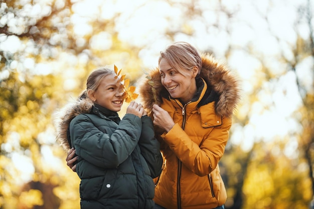 Piękna mama i jej szczęśliwa nastoletnia córka bawią się w parku, przytulają się i uśmiechają.