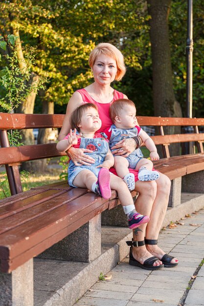 Piękna mama z córką i synem siedzą latem na ławce w parku