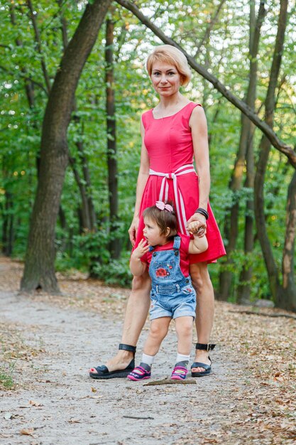 Piękna mama z córką spaceruje latem po parku