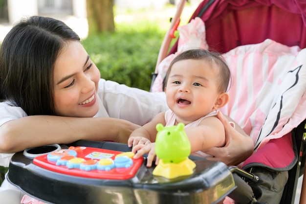 Piękna mama z dziewczynką siedzącą na wózku dziecięcym na świeżym powietrzu w słoneczny dzień