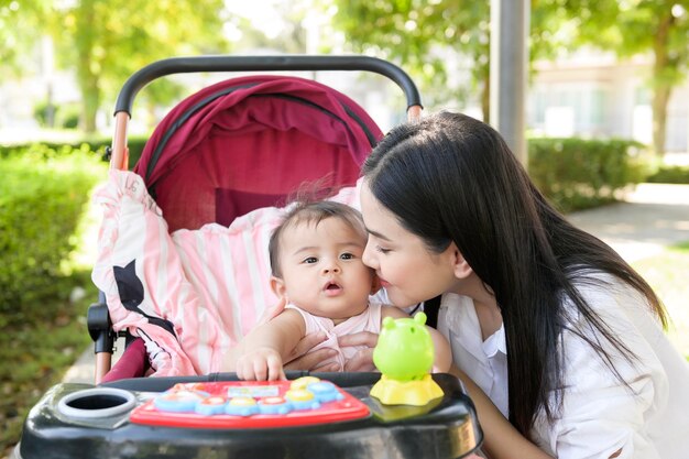 Piękna mama z dziewczynką siedzącą na wózku dziecięcym na świeżym powietrzu w słoneczny dzień