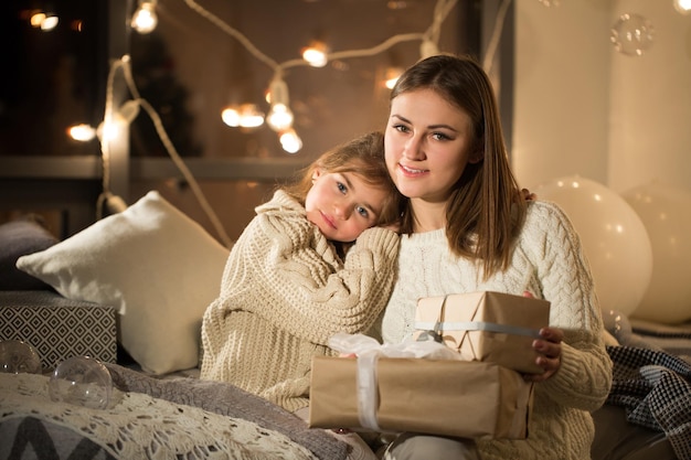 Piękna matka i córka otwierają magiczny prezent świąteczny w przytulnym wnętrzu domu Nowy rok