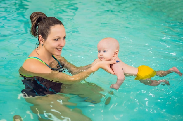 Piękna matka uczy ślicznej dziewczynki jak pływać w basenie Dziecko ma zabawę w wodzie z mamą