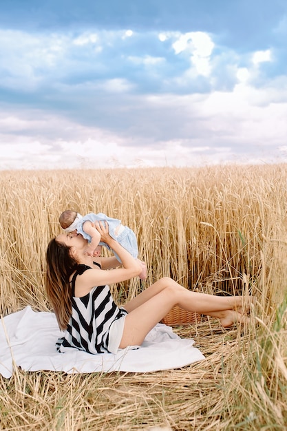 Piękna matka z dzieckiem w polu pszenicy