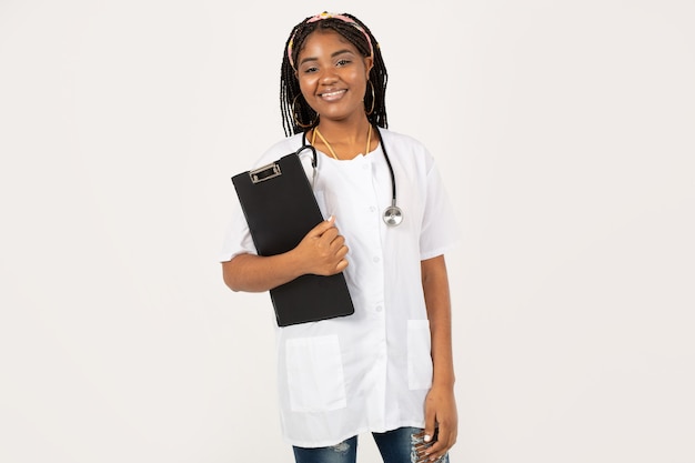 Piękna Młoda Afrykańska Kobieta Na Białym Tle W Fartuchu Medycznym Z Folderem