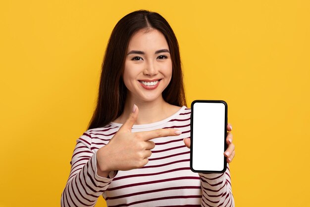 Piękna młoda Azjatka pokazuje telefon z białym ekranem