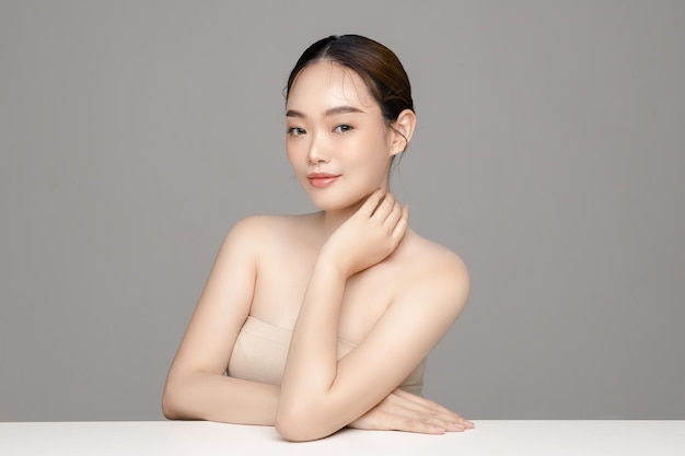 Piękna młoda Azjatycka kobieta model z idealnie czystą świeżą skórą na szarym tle Pielęgnacja twarzy Zabieg na twarz Kosmetologia Chirurgia plastyczna Piękny portret dziewczyny w studio