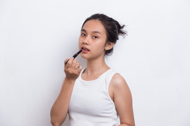 piękna młoda azjatycka kobieta używa szminki na białym tle