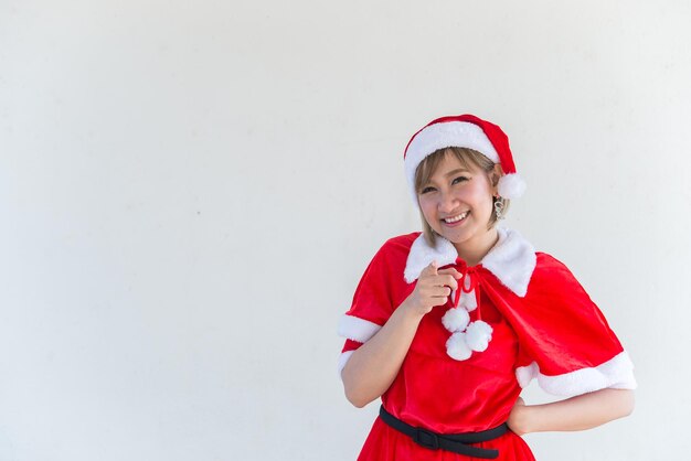 Piękna młoda azjatycka kobieta w Santa Claus ubrania na białym tleLudzie tajlandiiWysłane szczęście dla dzieciWesołych ŚwiątWitamy w zimieKoncepcja szczęśliwej kobiety