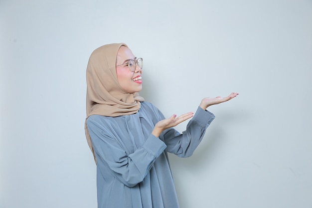 Piękna młoda azjatycka muzułmańska biznesowa kobieta w okularach wskazująca pusty obszar
