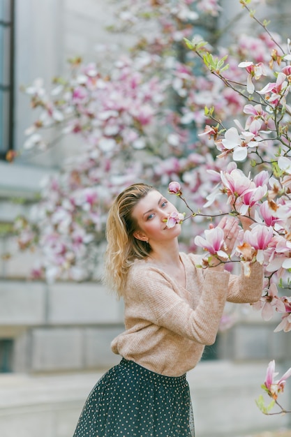 Piękna młoda blondynka w pobliżu kwitnącej magnolii