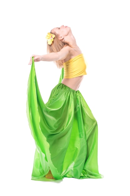 Zdjęcie piękna młoda blondynka w żółtym topie, długiej zielonej spódnicy i szpilce do włosów z kwiatkiem na głowie tańczy