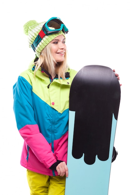 Piękna młoda blondynki kobieta w kolorowym śnieżnym żakiecie trzyma snowboard