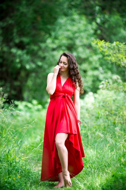 Piękna młoda brunetka kaukaski kobieta w czerwonej sukience na zewnątrz, portret pełnej długości