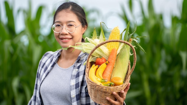 Piękna młoda brunetka Portret kobiety Farmer ręka trzyma warzywa w bambusowym koszu na zielono