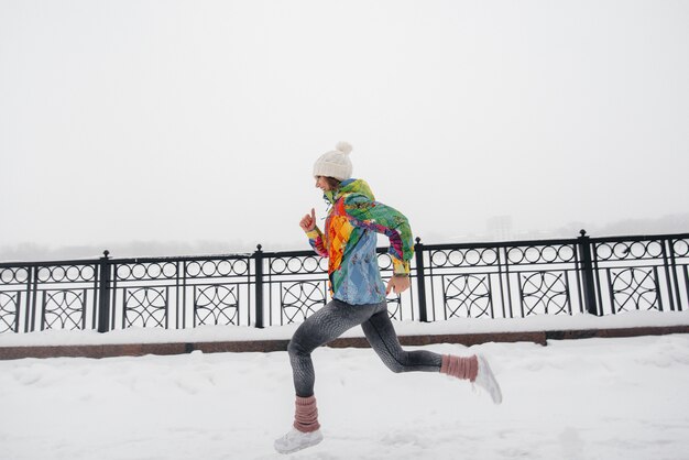 Piękna młoda dziewczyna Jogging w mroźny i śnieżny dzień. Sport, zdrowy styl życia