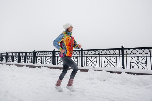 Piękna młoda dziewczyna Jogging w mroźny i śnieżny dzień. Sport, zdrowy styl życia