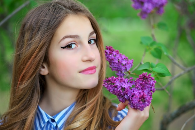 Piękna młoda dziewczyna nastolatka stojąca w kwiatach bzu.