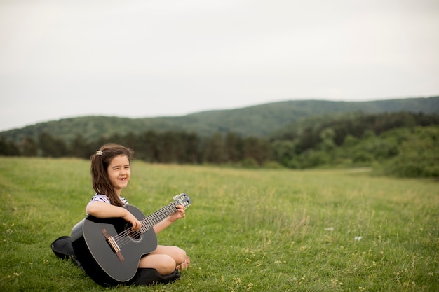 Piękna Młoda Dziewczyna Niesie Jej Gitarę W Naturze