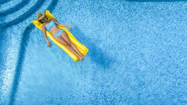 Piękna młoda dziewczyna relaks w basenie, kobieta pływa na nadmuchiwanym materacu i dobrze się bawi w wodzie na rodzinne wakacje, tropikalny ośrodek wypoczynkowy, widok z lotu ptaka z drona
