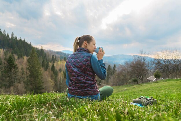 Piękna młoda dziewczyna relaksuje się w odpoczywającej naturze w górach