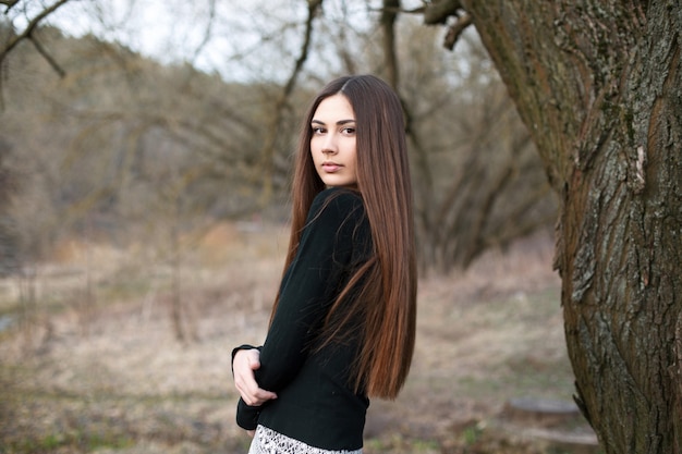 Piękna, młoda dziewczyna stojąca w pobliżu drzewa w ogrodzie