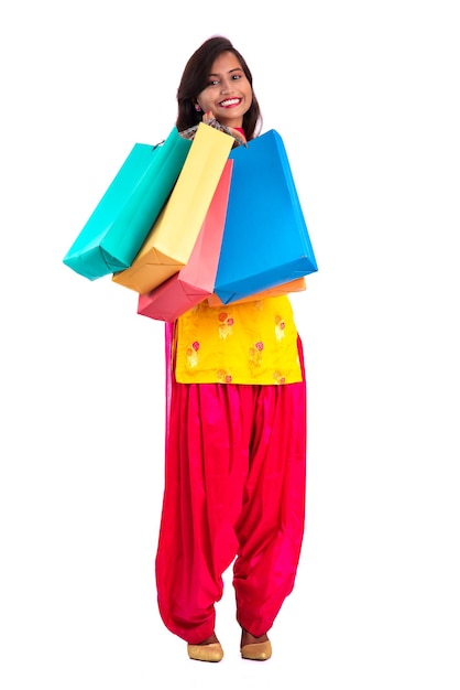 Piękna młoda dziewczyna trzyma i pozuje z torbami na zakupy na białym tle