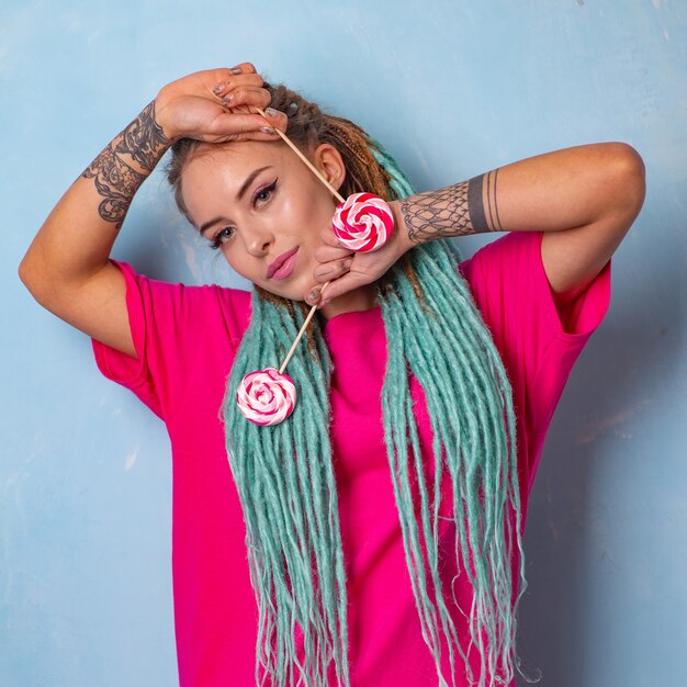 Piękna Młoda Dziewczyna Z Tatuażem I Dredami Pozuje W Różowej Koszulce Z Cukierkami Lizaki