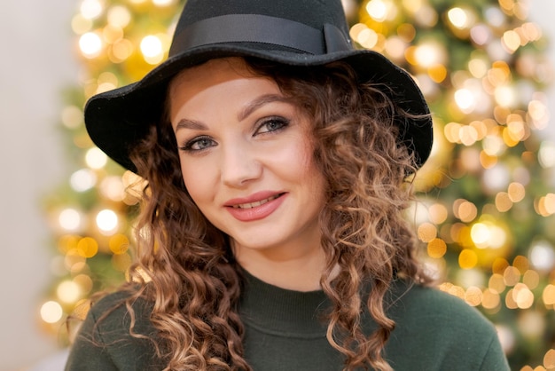 Piękna młoda kaukaska kobieta w zielonym swetrze i czarnym kapeluszu na głowie